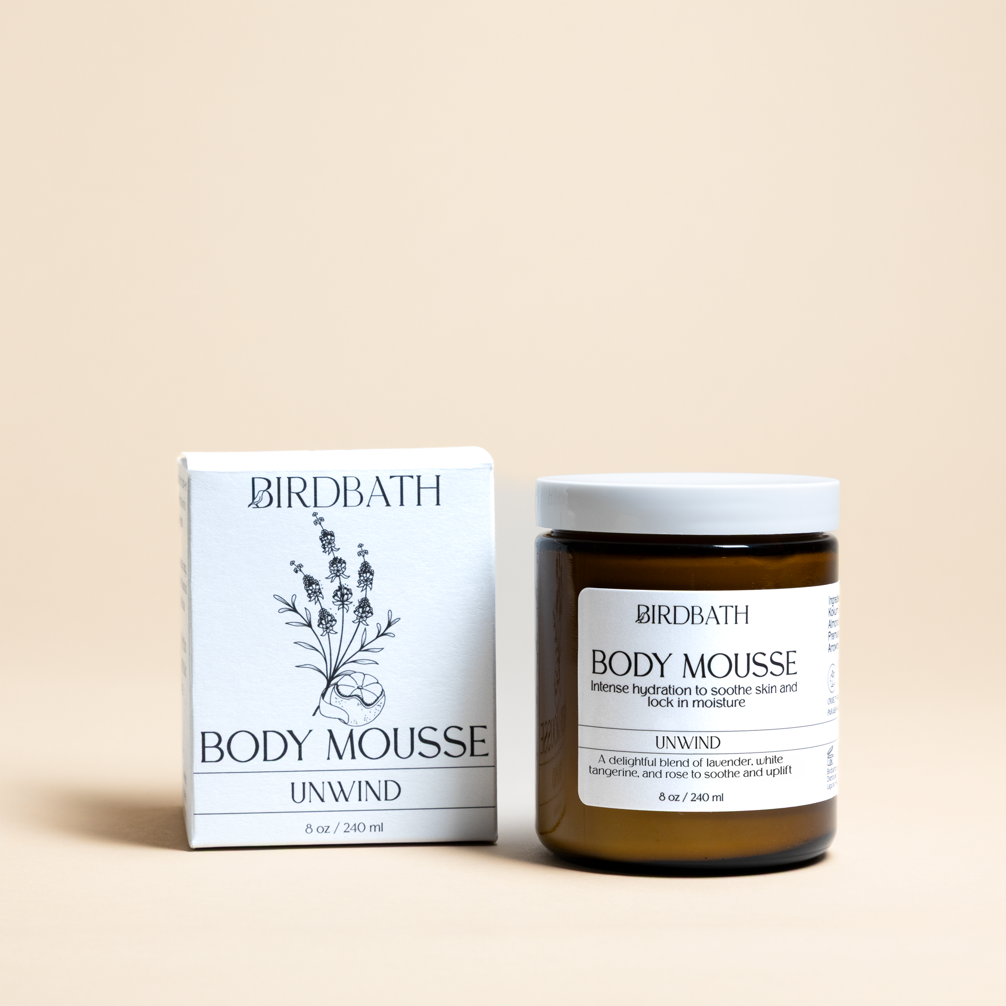 Birdbath Unwind Body Mousse jar with a white product box on a cream background.