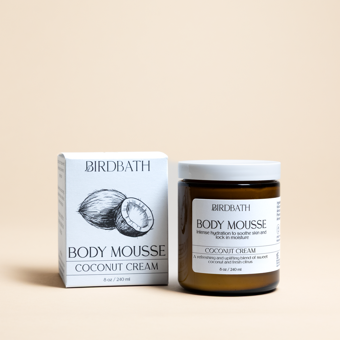 Birdbath coconut cream Body Mousse jar with a white product box on a cream background.